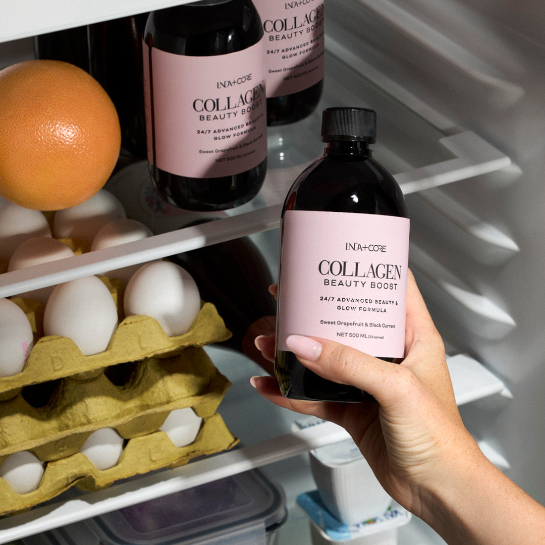 En hånd tar en flaske Collagen Beauty Boost ut av kjøleskapet